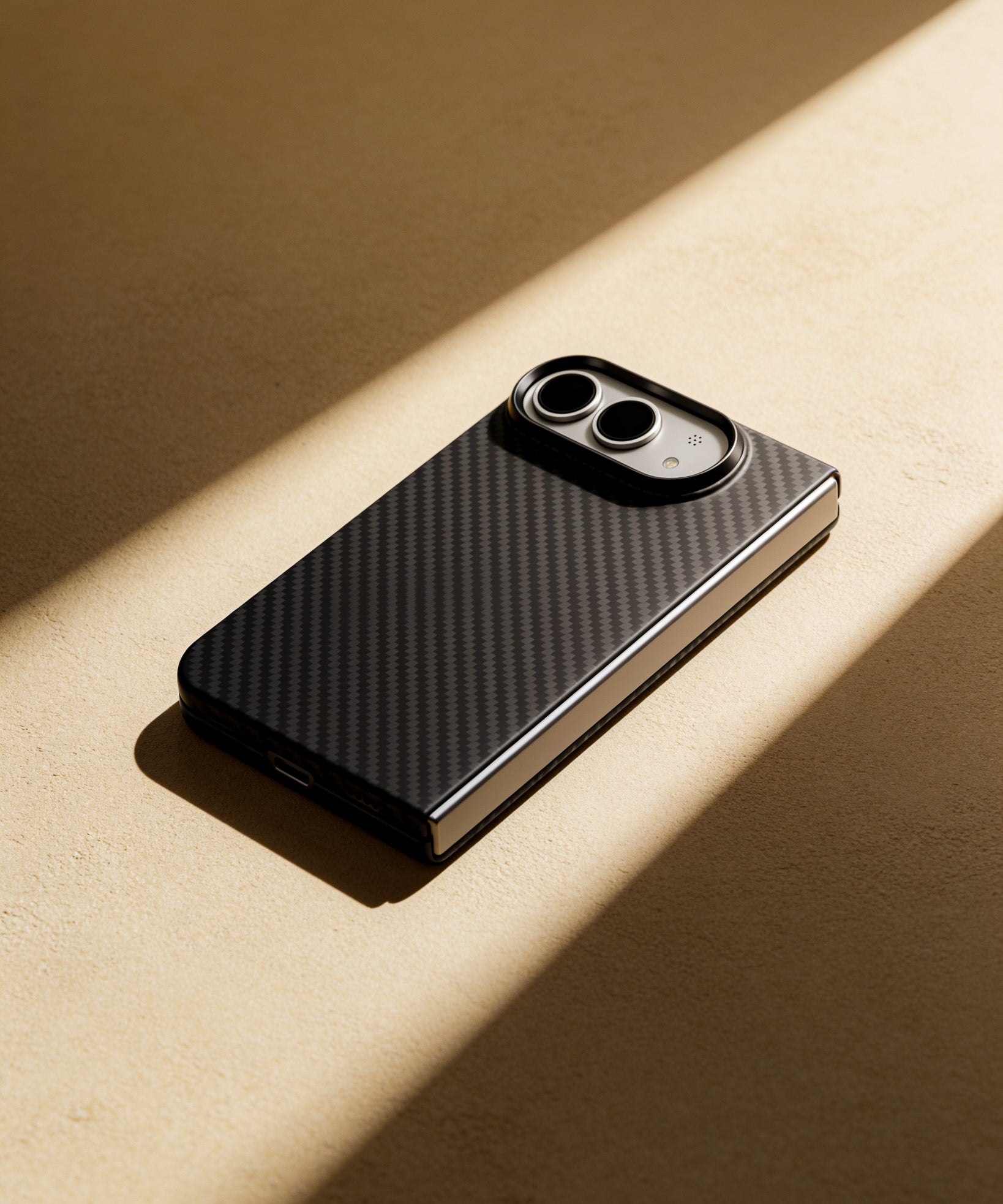A smartphone case with a black carbon fiber pattern and a black camera ring, shown on a beige surface with dramatic diagonal sunlight casting shadows.