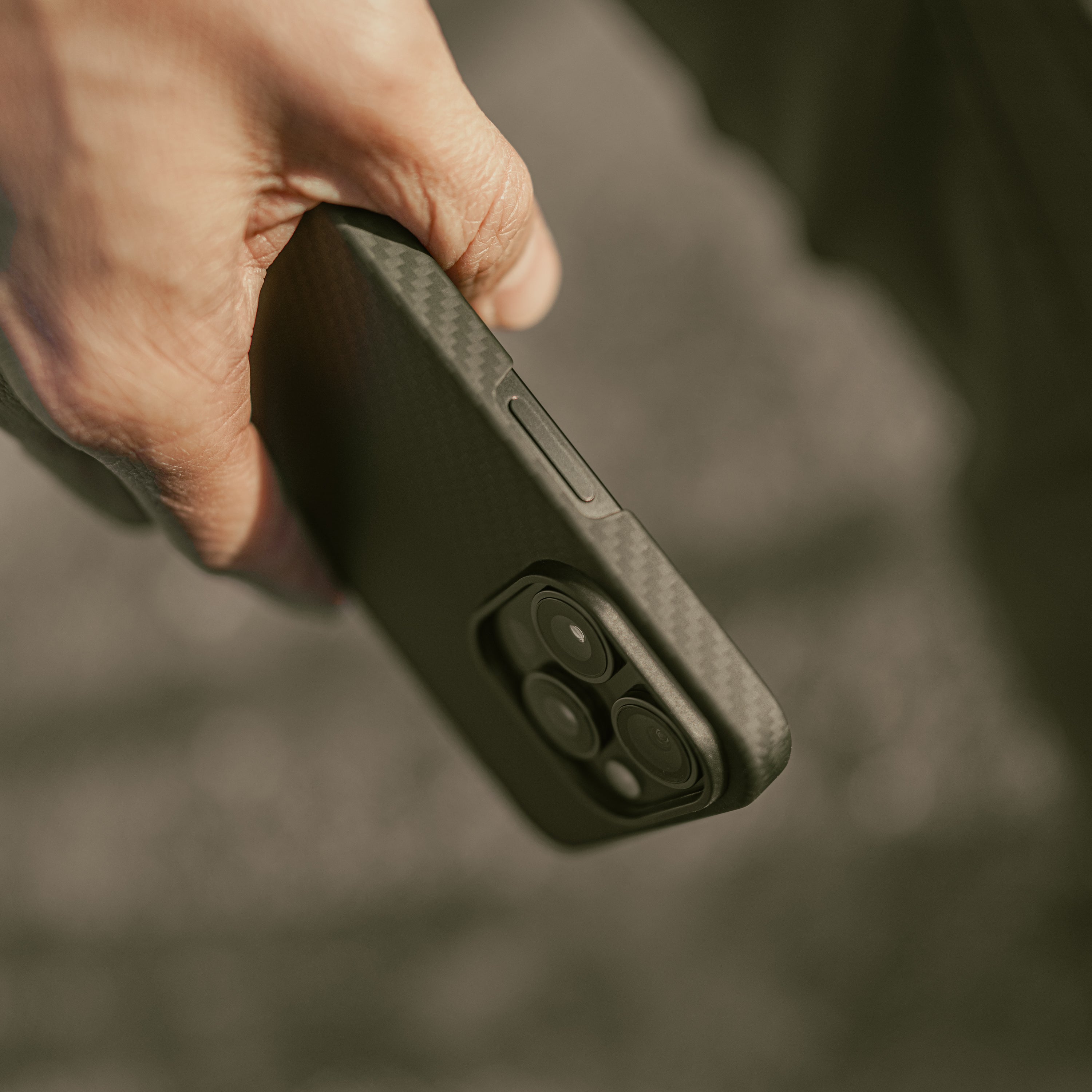 Mason aramid fiber iPhone case in matte black, held in hand, showing the smooth matte grip